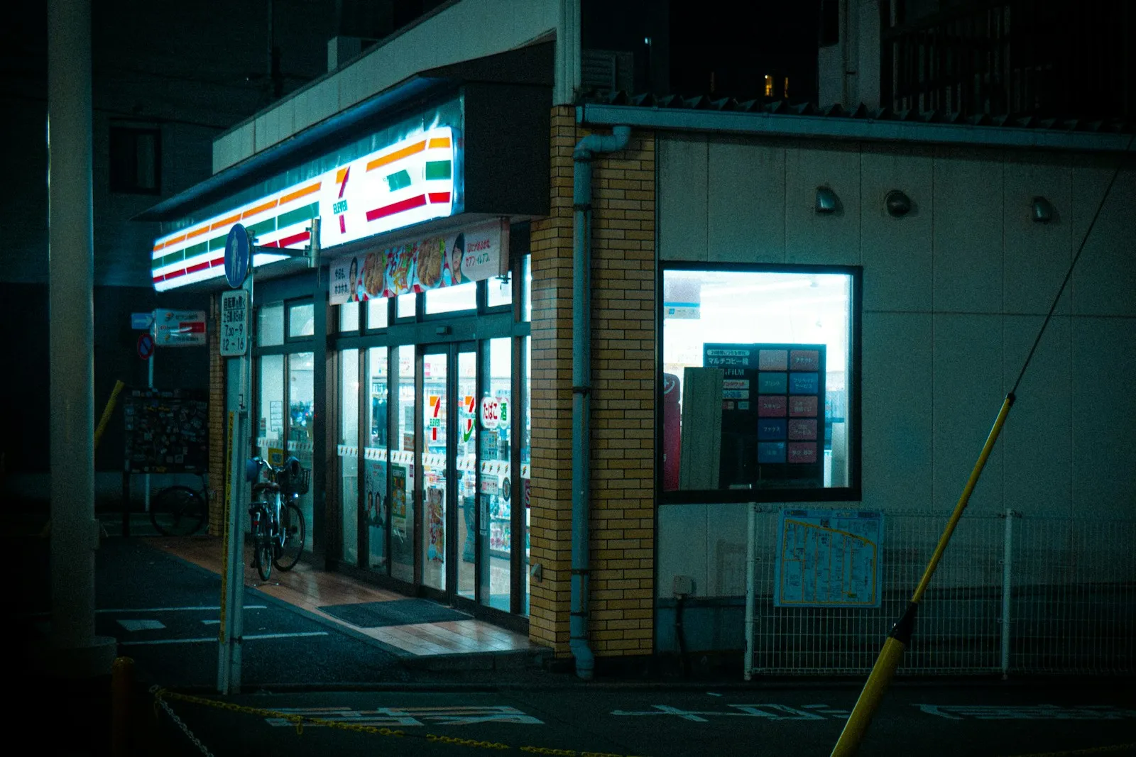 A brightly lit Japanese convenience store on a street at night.
