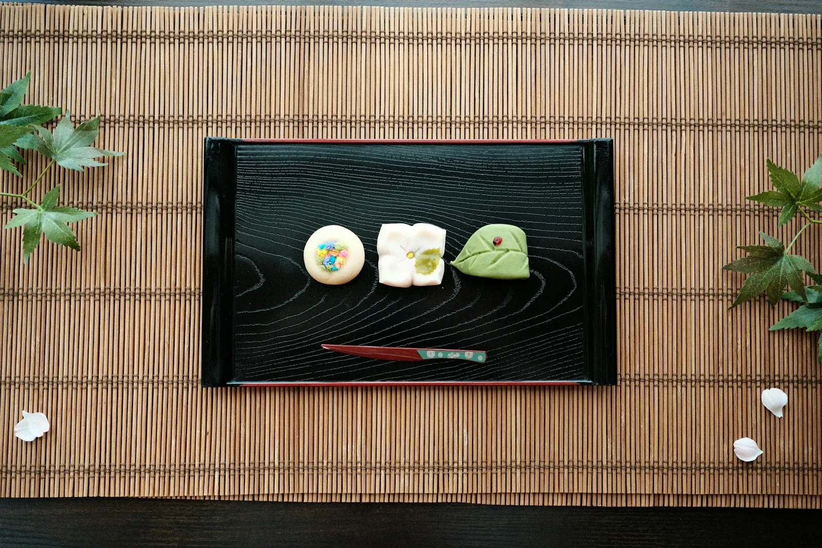 Three traditional Japanese sweets arranged on a black tray.