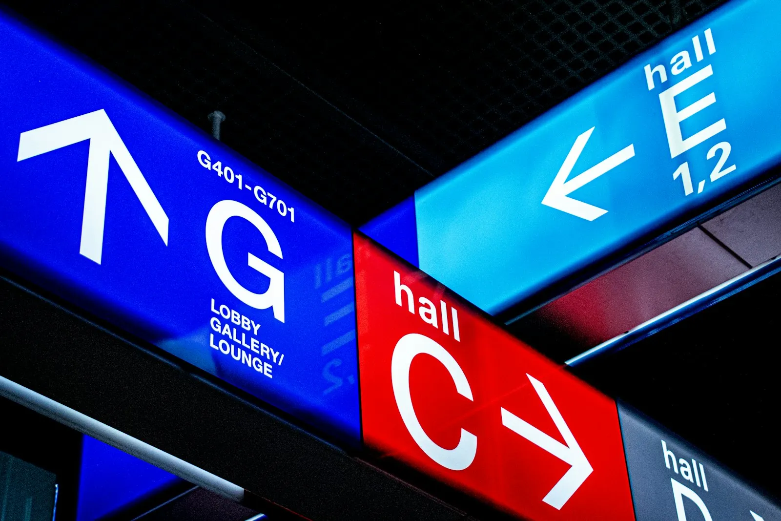 Overhead direction signs pointing to airport halls and the lobby.