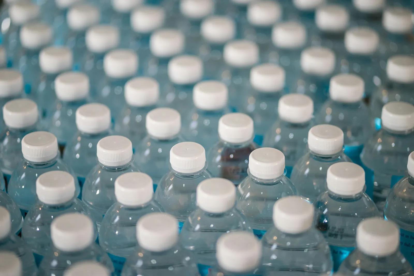 Rows of clear plastic water bottles with white caps, seen from above.