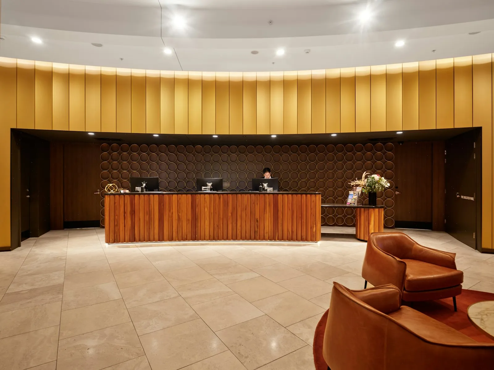 A hotel reception desk with a wooden counter and lobby seating.
