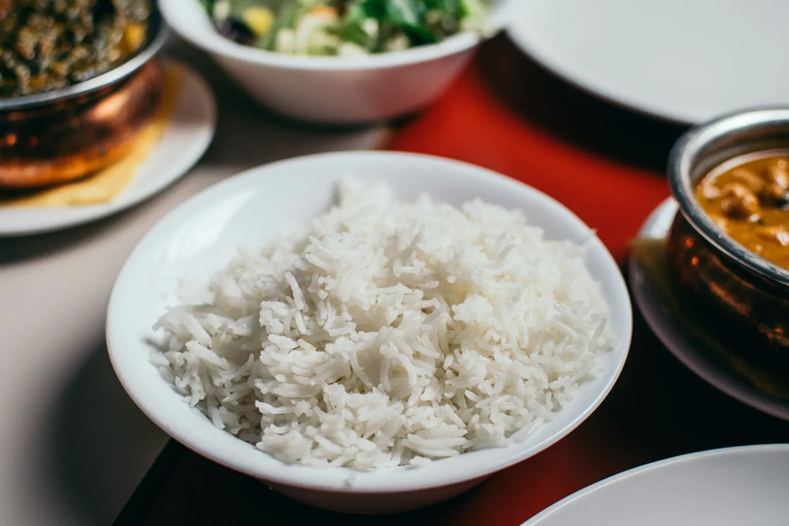 A plate of cooked white rice next to other dishes.