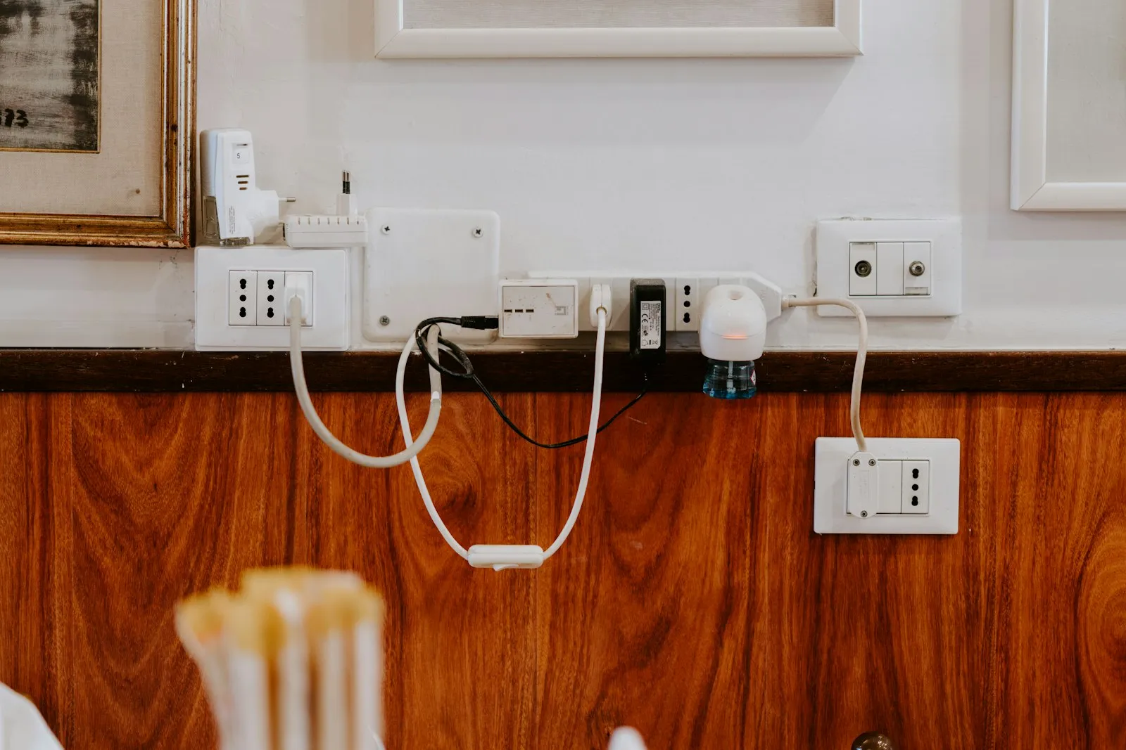 Several wall sockets of different shapes with cables and an adapter plugged in.