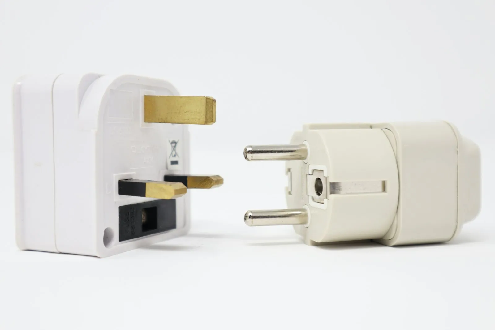 Two white travel plug adapters with different pin shapes.