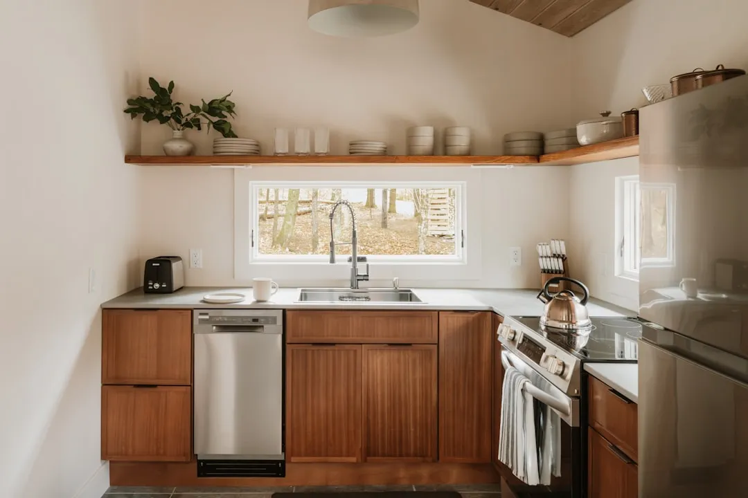 A domestic kitchen with wooden cabinets, stainless steel appliances and a wall outlet above the counter.