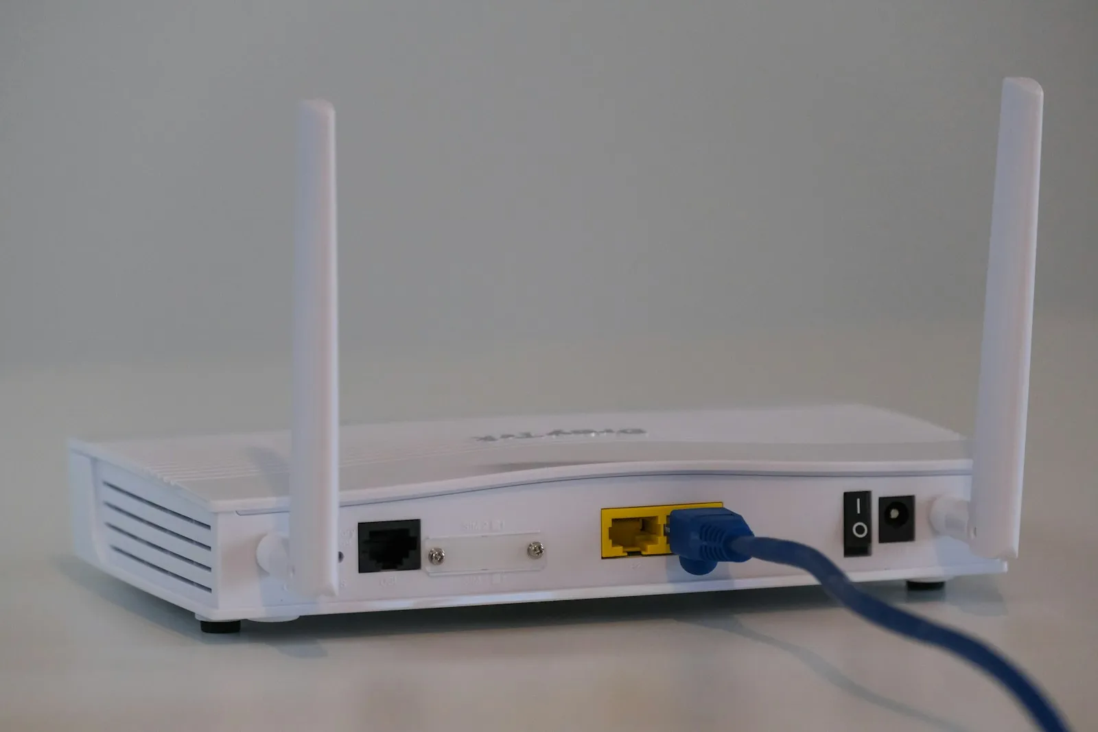 A white wireless router with two antennas and a network cable attached.